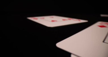 Oyuncu kumarhanede siyah masada farklı takımların kartlarını dağıtır. Poker destesi, karanlık yüzeye dağınık bir şekilde dağıtılmış oyun kartları.