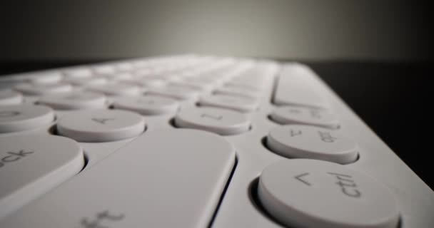 暗いテーブルの上に横たわる白いコンピュータのキーボードの詳細なボタン オフィスでの作業のための準備ができてテキストと数字を入力するための現代の入力デバイス — ストック動画