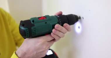 İşçi ağır çekimde elektrikli tornavidayla vidaları duvardan söküyor. İnşaatçı tamir sırasında vidayı alçıpandan kaldırır