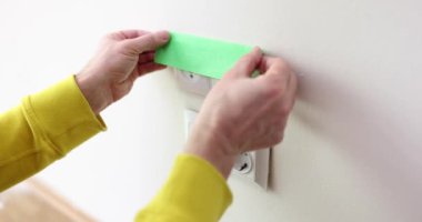 Tamirci, odadaki boya lekelerinden korumak için sokete yapıştırıcı yapıştırır. İşçi toprağa çarpmasını önlemek için kapağı sıva ile kapatır