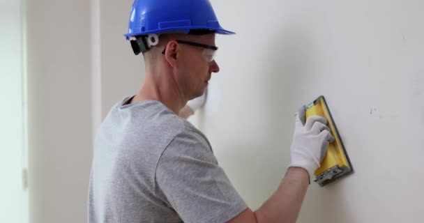 在更新改造的房间里 工人们用手工砂纸擦拭墙壁 钢盔磨床在修整过程中的粘贴表面 — 图库视频影像