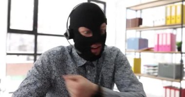 Maskeli ve kulaklıklı bir adam online hırsızlığın olası kurbanıyla görüntülü görüşme yapıyor. Sahtekarlık, hayali projeye yatırım yapmaya ikna etti.