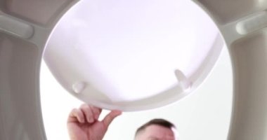 Meraklı adam, beyaz seramik klozetin kapağını açar. Gözlerini kocaman bir deliğe çevirir. Erkek kişi evdeki tuvaleti temizlemeye hazırlanıyor.