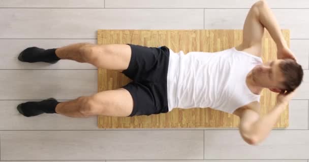 Sportowy Człowiek Pompuje Mięśnie Brzucha Leżące Drewnianym Panelu Laminowanej Podłodze — Wideo stockowe