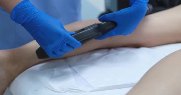 橡胶手套专家使用现代激光设备剪毛客户的腿 女人躺在沙发上接受美容院的手术 — 图库视频影像