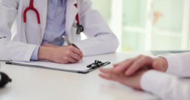 Kadın doktor, not defterine tıbbi geçmiş listesini dolduruyor. Tıbbi bakım ve sigorta