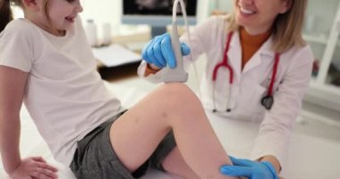 Doktor, çocuk kliniğinde diz eklemini ultrasonla muayene ediyor. Çocuklarda kemik hastalıklarının teşhisi ve menisküs ağrıları