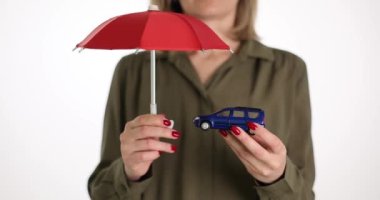Kadın arabanın üzerinde şemsiye tutuyor. Araba koruma sembolü. Otomobil sigortası ve nakit ödemeler