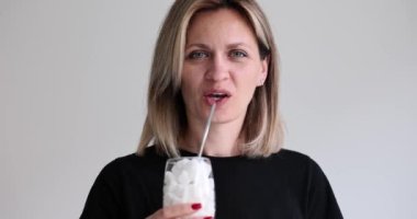 Bir bardak şekerden samanla içen güzel bir kadının portresi. Şeker küpleriyle dolu bardaklar