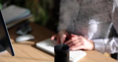 Çalışma saatleri içinde modern hava nemlendirici cihazı. Yönetici internetteki bilgisayar işlerini kullanıyor, yayıcının aromaterapi buharının tadını çıkarıyor.