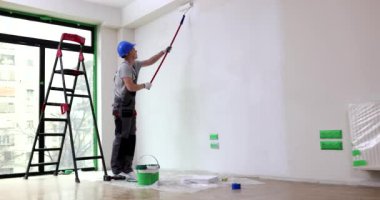 Beyaz boya silindirli duvarlar boyuyor. Beyaz boyalı silindir ile çıplak duvar boyamak