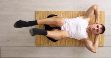 Sağlıklı genç adam paspas üzerinde egzersiz yapıyor ve basın için egzersiz yapıyor. Spor eğitimi.