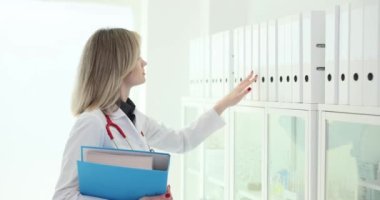 Doktor, ofis 4K filminde ağır çekimde dokümanların olduğu dosyayı arıyor. Tıp konsepti evrak organizasyonu