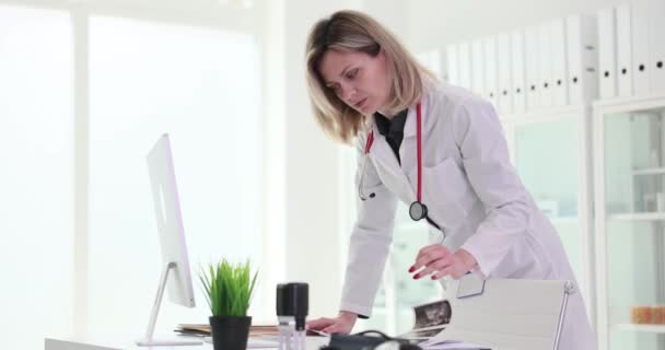 의사는 컴퓨터에 정보와 클리닉 영화의 동작에 환자의 기록을 합니다 문서의 — 비디오