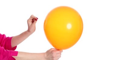 Beyaz arka plan 4K filminde güvenlik iğnesiyle turuncu bir balonu patlatmak. Gerçekleştirilemez rüya kavramı