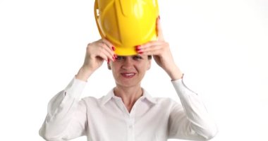 Kadın mühendis sarı koruyucu inşaat başlığı takıyor. Beyaz arka planda 4K film yavaş çekim. İnşaat alanı kavramında güvenlik