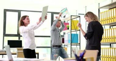 Başarılı iş arkadaşları ellerinde 4K filmle ofiste dans ediyorlar. Kurumsal zafer kavramı