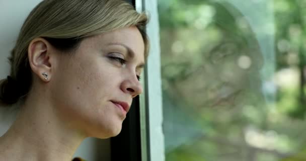 悲しい女性が退屈され 窓の外を見る4K映画スローモーション 孤独の概念からのストレスとうつ病 — ストック動画