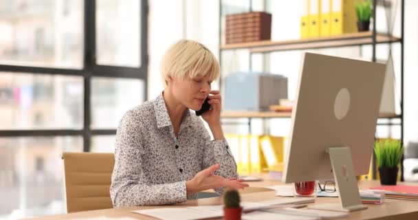 女性マネージャーは積極的に電話で話す顧客との取り引きを論議する 女性従業員は職場に座って顧客とオンライン注文の詳細をチェック — ストック動画