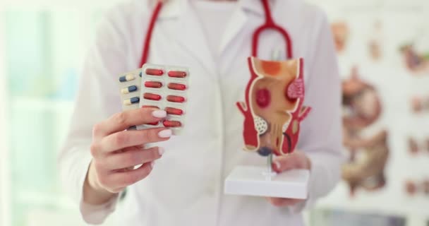 穿着工作服的女医生手里拿着药丸泡和带有病理学的直肠模型 诊所内器官疾病的概念及治疗 — 图库视频影像