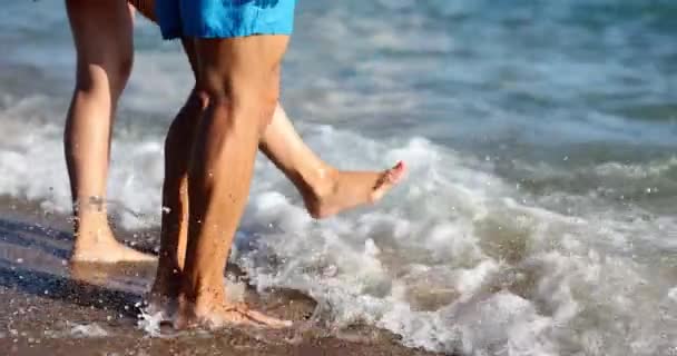 人々はビーチのリゾートで素足で海の波を転がすキック アクティブな観光客はビーチで一日を楽しむ カップル休暇とエンターテイメントの海辺のスローモーション — ストック動画