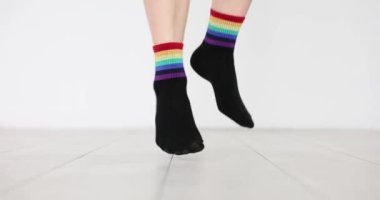 Üzerinde gökkuşağı resmi olan siyah çoraplar giymiş ayaklar. Beyaz arka planda LGBTQ bayrak dekoru olan kıyafetler. Hassas sosyal gruplara destek