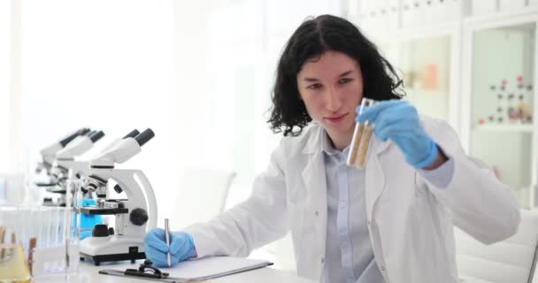 화학자는 결과에 노트를 시험관에서 샘플을 봅니다 사람은 실험실에서 자료를 조사한다 — 비디오