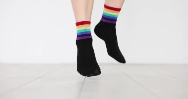 虹の旗をイメージした黒い靴下に身を包んだ足を踏んでください 白い背景にLgbtqの旗の装飾が施された服 脆弱な社会集団への支援 — ストック動画