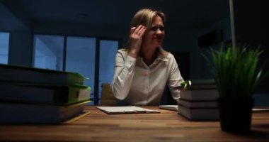 Yorgun iş kadını karanlık ofiste parmaklarıyla tapınaklara masaj yapıyor. Başı ağrıyan yorgun bayan çalışanlar fırtına sırasında geç saatlere kadar çalışırlar.