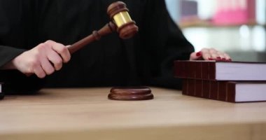 Siyah mantolu yargıç tahta masada oturan tokmağı vurdu. Kadın, mahkeme salonunda kanun kitaplarına adalet sembolü olarak el koydu.