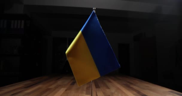 暗い会議室で木製のボードテーブルの上にインストールされているさまざまな国の旗 ウクライナを支援するための効果的な共同活動のための国際協力 — ストック動画