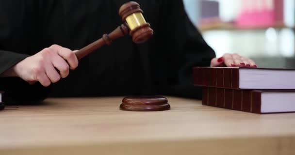 身穿黑色斗篷的裁判坐在木制桌旁的音块上敲着木槌 妇女在法庭上把立法书当作正义的象征 这是一项缓慢的运动 — 图库视频影像