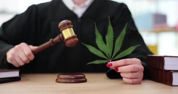 黒いマントルの裁判官は大麻の葉を手にした健全なブロックに砂利を打つ 裁判所の労働者は違法マリファナの成長の遅い動きのための評決を — ストック動画