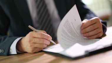 İşadamı, yakın çekimde imzalamak için kağıtları karıştırıyor. Yasal sözleşme şartları