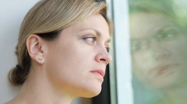 Üzgün kadın sıkılır ve pencereden dışarı bakar. Yalnızlık konseptinden dolayı stres ve depresyon