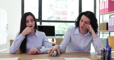 Sıkıcı birkaç ofis çalışanı önemli bir telefon bekliyor. Erkek ve kadın çalışanlar iş yerinde gergin bir şekilde cep telefonuna bakarlar.