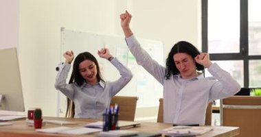 Büro çalışanları sıkı çalışmayı bitirdikten sonra eğleniyor. Genç adam ve kadın ofiste masa başında dans ediyorlar. Başarılı girişimciler projenin yavaş çekimde tamamlanışını kutladılar