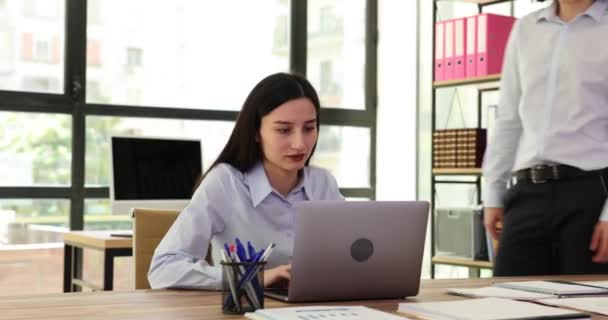 男性従業員は女性の同僚に近づき ノートパソコンの描画の注意を閉じます 勤務中はマネージャーが楽しく話をする — ストック動画
