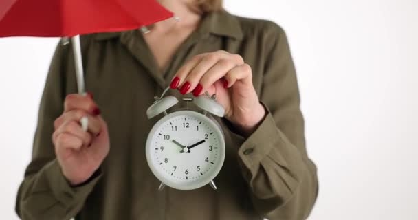 女性は白い背景に白い目覚まし時計と赤い傘を持っています 時間管理と組織の概念 締切日意識 — ストック動画