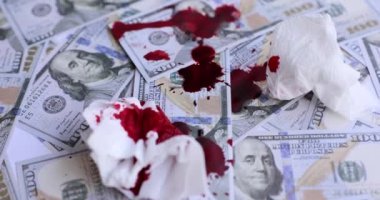 Koyu kırmızı kan damlaları dağınık dolar banknotlarının ve peçetelerin üzerine düşer. Finansal kazanç için suç. Kirli para ve aldatma konsepti yavaş çekim