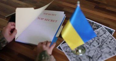 Ordu komutanı karşı saldırı hakkında gizli belgeler üzerinde çalışıyor. Adam uydu görüntüleri ve Ukrayna bayrağıyla masada oturuyor.