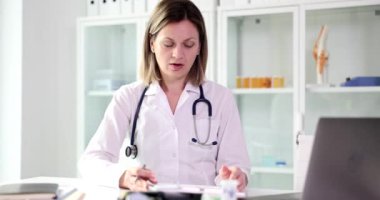 Kadın doktor, panoda hayal kırıklığına uğramış olarak rapor okuyor. Üzgün kadın elleri ile yüzünü kapatıyor. Klinikte ağır çekimde oturuyor.