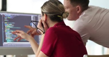 Programcılar ofiste monitörle kod yapısını tartışıyor. Proje yöneticisi ve mühendis dijital verileri kontrol ediyor. Yavaş çekimde gelişen sistem desteği kavramı