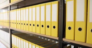 Sarı klasör yapısı ve şirket ofisindeki raflarda malzemeler. Arşiv odası ve dokümanların yüzük klasörlerinde saklanması için. Veri kaydetme kavramı