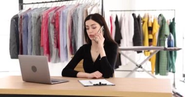 Kadın işçi telefonda konuşur ve çamaşır odasındaki iş yerinde oturan not panosuna not alır. Kuru temizleme yöneticisi, sıralama detaylarını istemci yavaş çekim ile tartışır