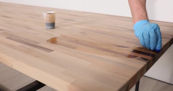 ゴム手袋の男の従業員は オフィスの職場でニスの木製の床面で研磨します 大工は液体漆の遅い動きを使用します — ストック動画