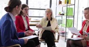 Meslektaşlar şirket önermelerinde koltuklarda oturan verilerle belgeleri paylaşırlar. İş yeri konseptinde proje geliştirme. Ofiste takım çalışması ağır çekimde