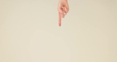 Kadın eli aşağı doğru işaret parmağıyla stüdyoda beyaz duvara doğru gidiyor. Küçük nazik el işaretleri bilinmeyen objeye işaret parmağı yavaş çekim