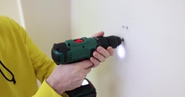 İşçi prizde vidaları elektrikli tornavidayla söker. Dairelerin onarımı ve dönüşümü. Kurucu vidayı ağır çekimde alçıpandan kaldırır