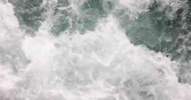 Köpüklü sürat teknesi güneşli bir günde deniz yüzeyinde dalgalar oluşturuyor. Açık denizde yelkenli yatın arkasında dönen su. Tatil eğlencesi ve ağır çekimde seyahat